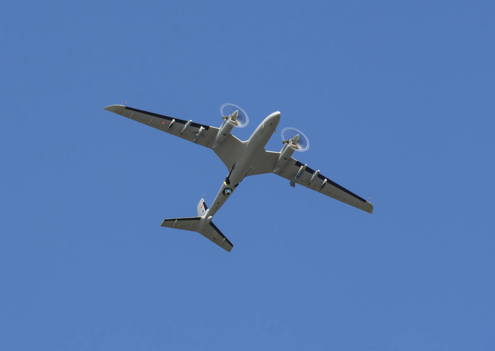 Aerial view of a drone aircraft cruising through a clear blue sky, showcasing modern aviation technology.