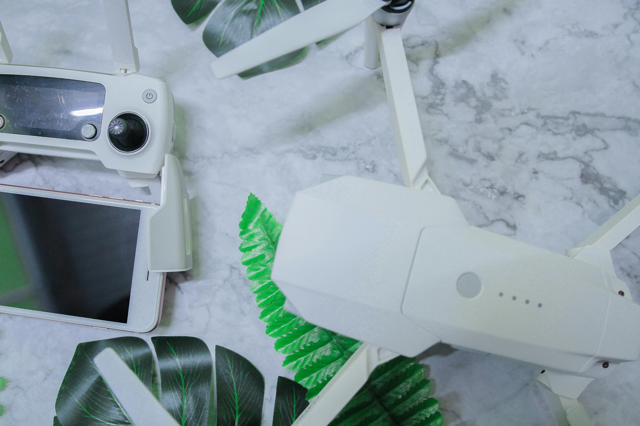 From above of white drone gadget placed near electronic devices with controller and smartphone during home recording lesson in daytime